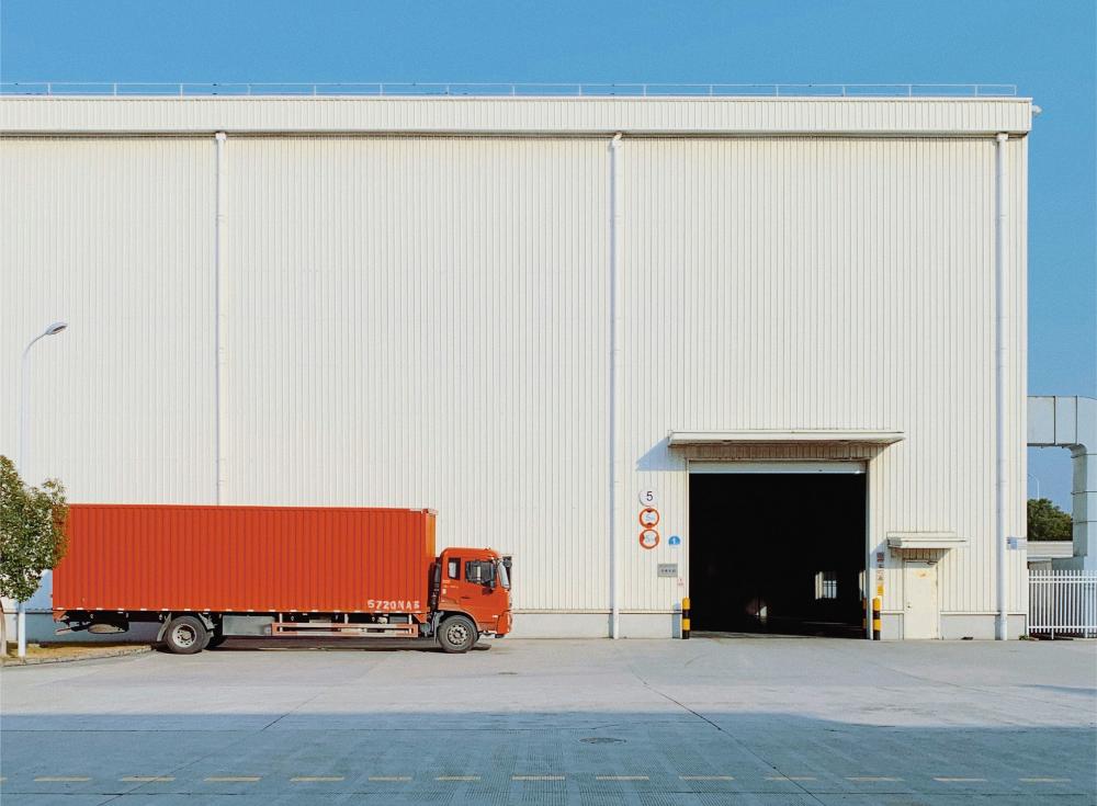 Red truck parked outside large warehouse